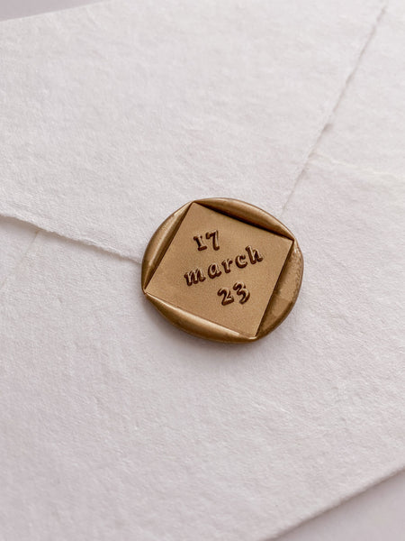 Diamond shaped personalized date custom wax seal in gold on beige handmade paper envelope