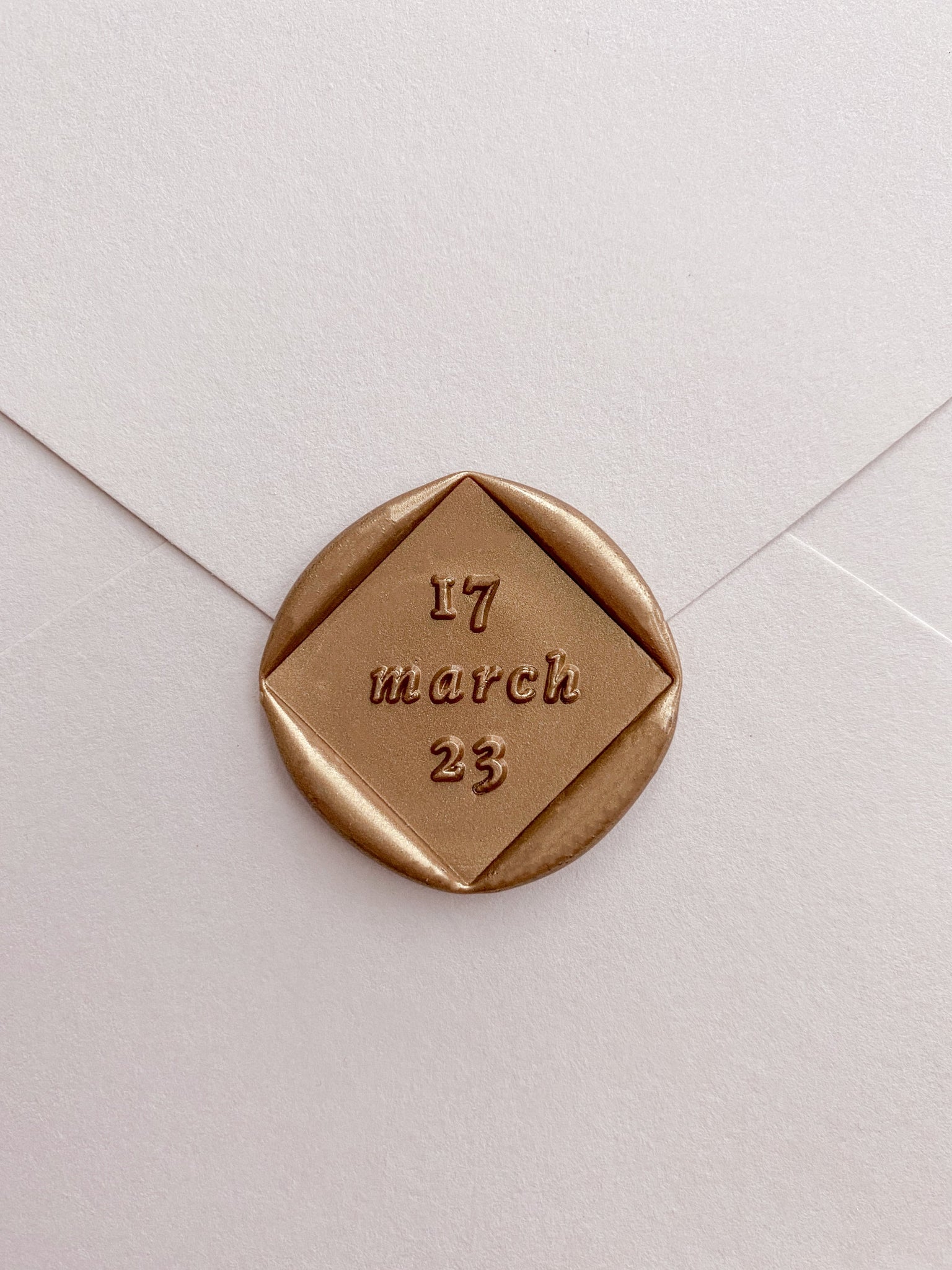 Diamond shaped personalized date wax seal in gold on paper envelope_front angle