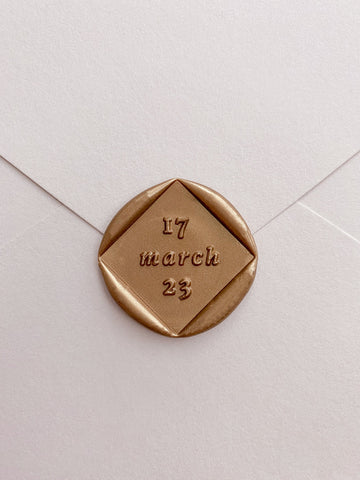 Diamond shaped personalized date custom wax seal in gold on beige paper envelope
