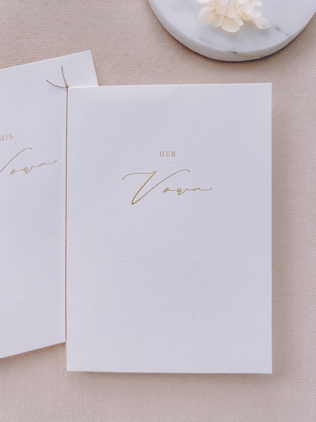 A set of two His and Her gold foil white vow books in calligraphy script with fine brown twine