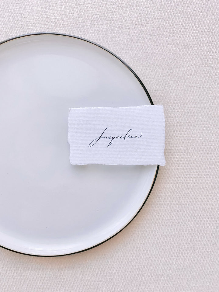handmade paper place card in white color hand lettered in modern calligraphy in black ink_front angle