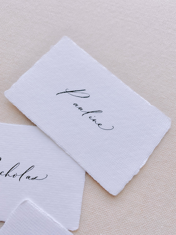 handmade paper place card in white color hand lettered in modern calligraphy in black ink_closeup side angle