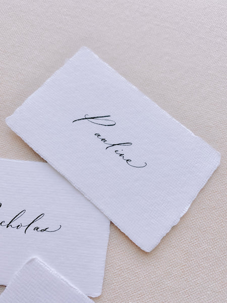 handmade paper place card in white color hand lettered in modern calligraphy in black ink_closeup side angle