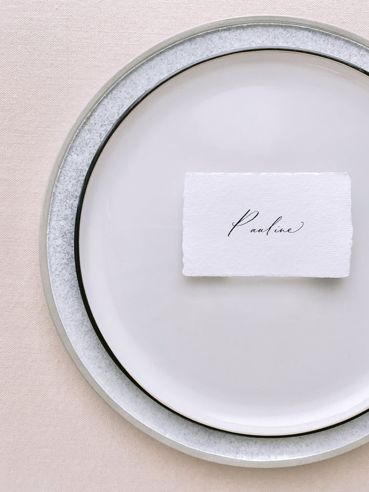 handmade paper place card in white color hand lettered in modern calligraphy in black ink