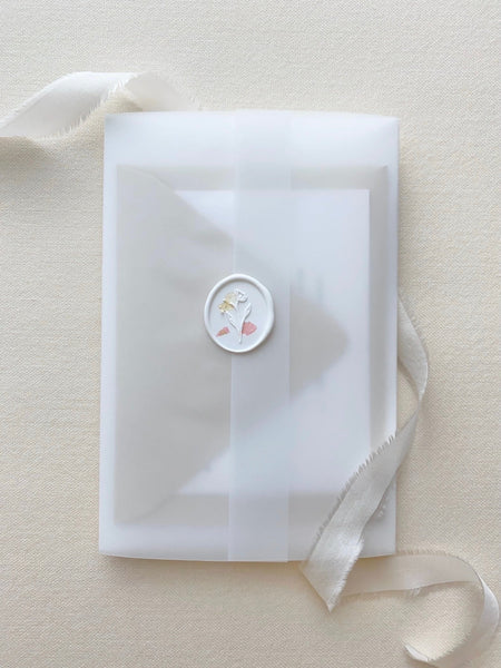 a white oval wax seal sticker with blush color dried petals on a vellum envelope