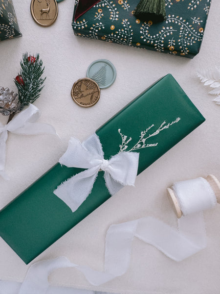 Christmas gift wrapped in white silk ribbon next to some holiday design wax seals