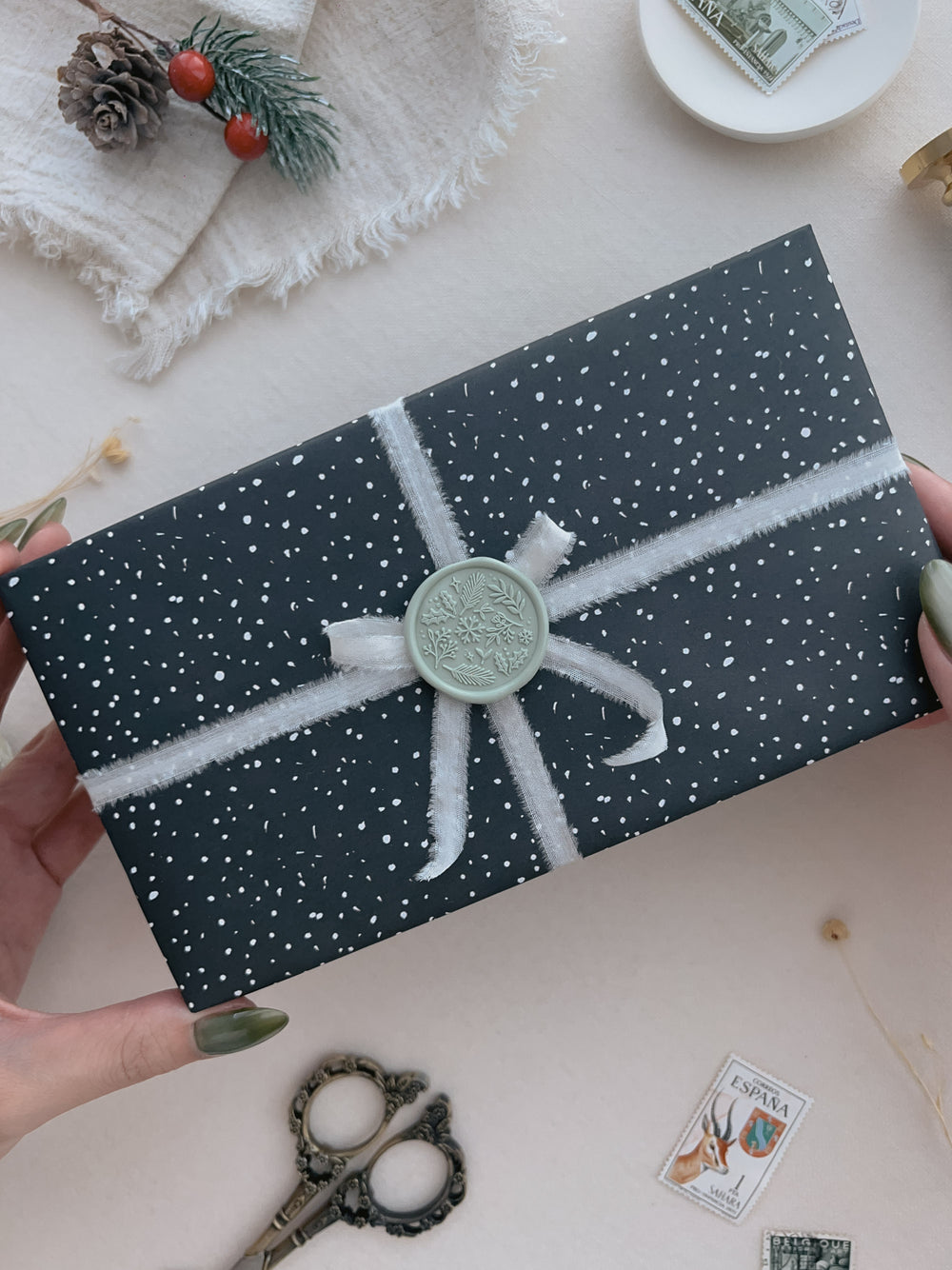 Light sage green winter botanical wax seal on a wrapped Christmas gift