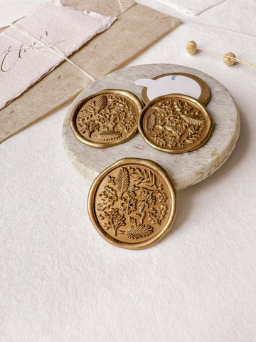 Winter garden wax seals in gold styled with a small gray stone dish, handmade paper and a dried floral branch
